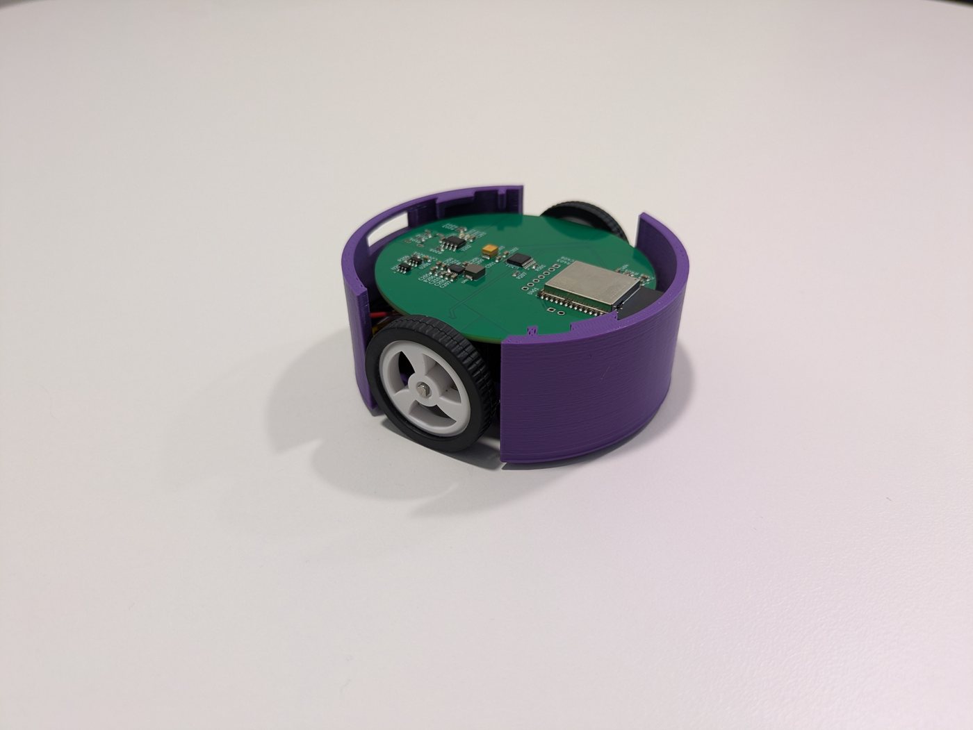 A pod with its lid off: the purple printed body, the green circuit board and a wheel.