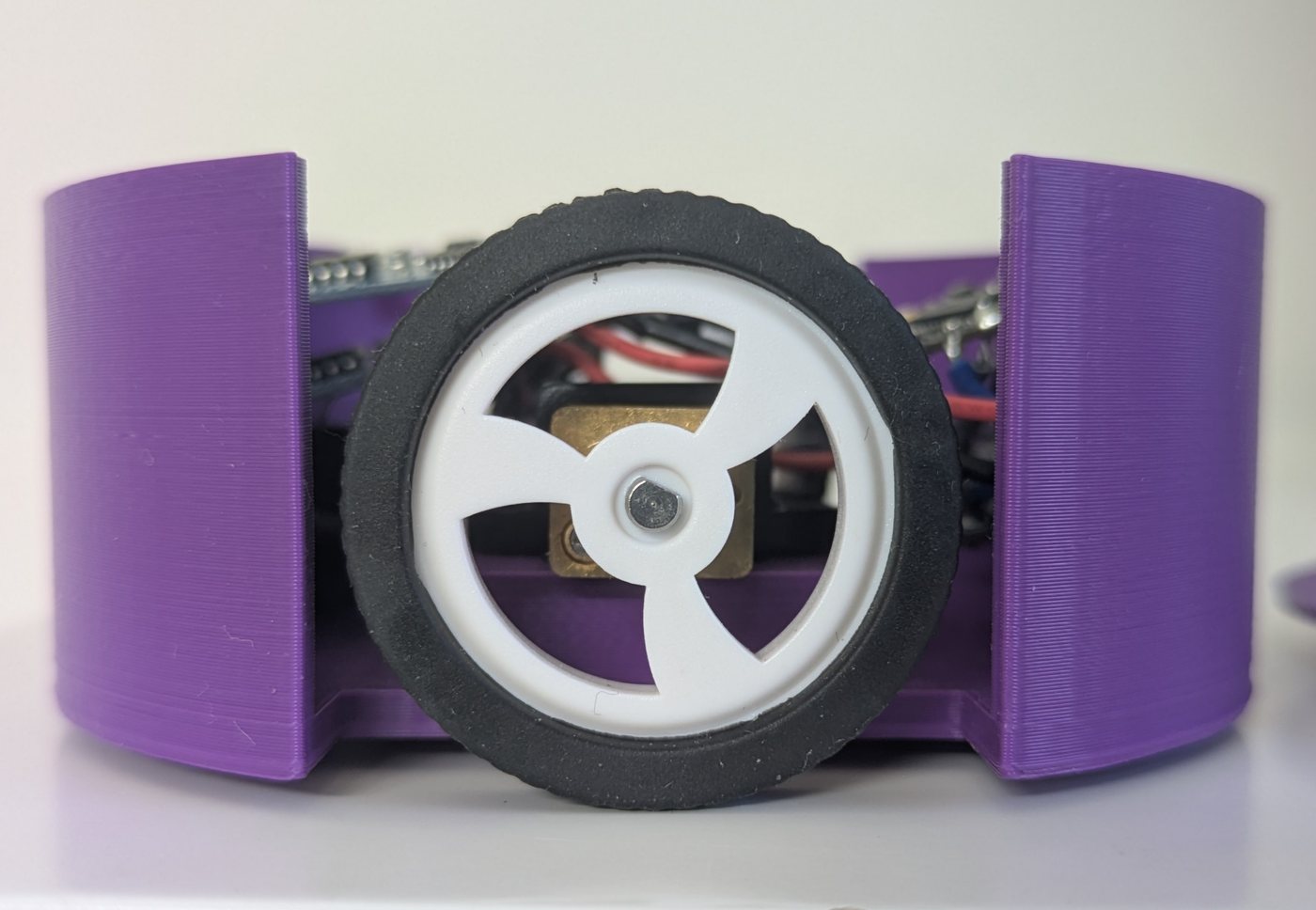A pod from the side: a rubber wheel with a white three-spoke hub in the body's slot.